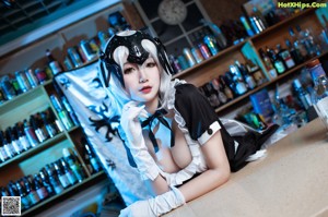 A woman in a maid outfit sitting on a chair.