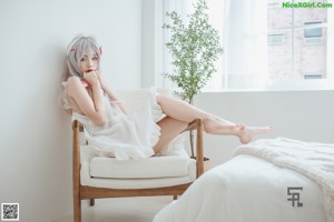 A woman sitting on a wooden chair in a room.