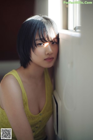 A woman in a yellow top is posing for a picture.