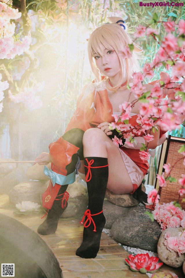 A woman sitting on a rock in front of a flowering tree.