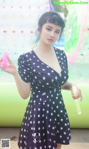 A woman in a white dress holding an orange in her hand.
