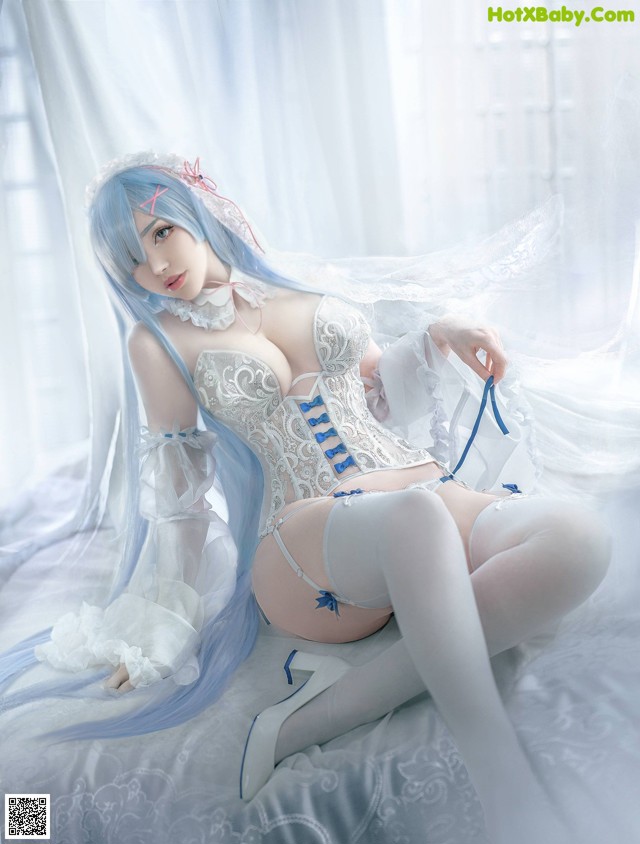 A woman in a white corset and stockings sitting on a bed.