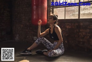 A woman wearing headphones standing in front of a brick wall.