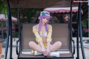 A woman with long purple hair sitting on a chair.