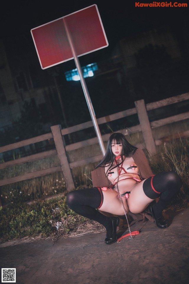 A woman sitting on the ground next to a no crossing sign.