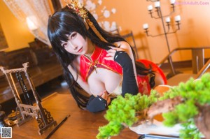 A woman in a red and black outfit sitting on a wooden floor.