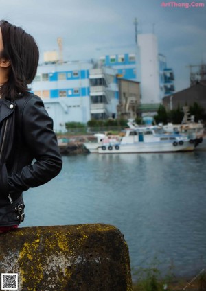 A woman in a black leather jacket and plaid skirt posing for a picture.