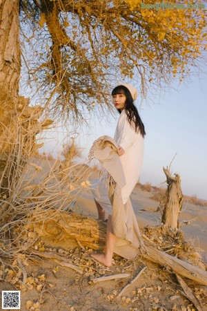 A woman with long brown hair sitting on a beach.