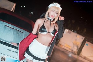 A woman in a bikini standing next to a white car.