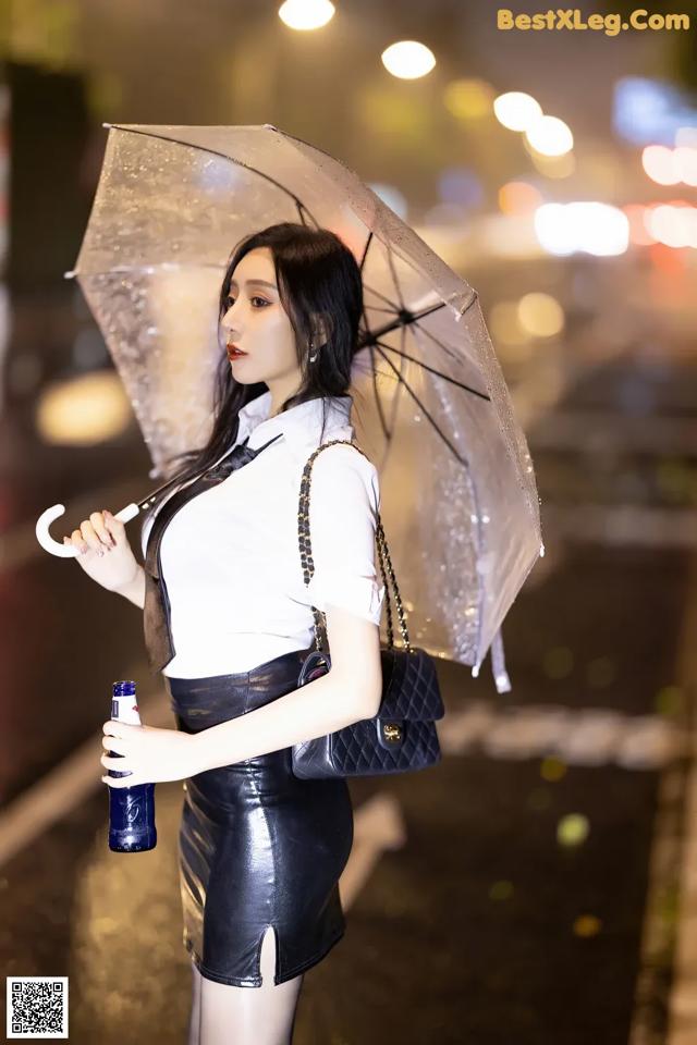 A woman holding an umbrella while walking down the street.