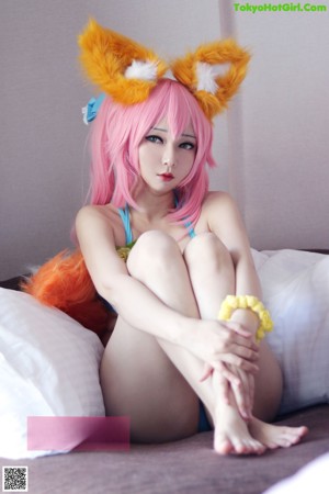 A woman in a bikini sitting on a bed with a fox tail.