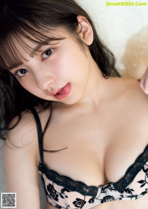 A woman in a pink lingerie sitting on a bed.