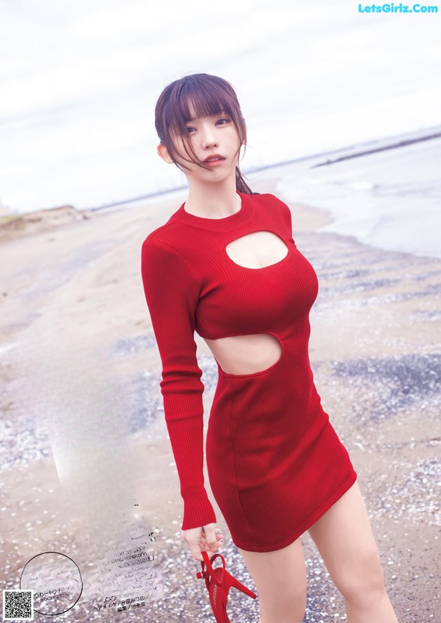 A woman in a red dress standing on a beach.