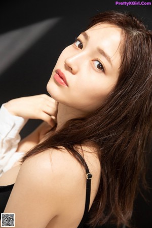 A woman in a black and white shirt leaning against a door.