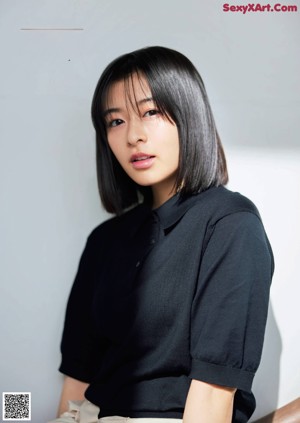 A woman in a white shirt sitting on a chair.