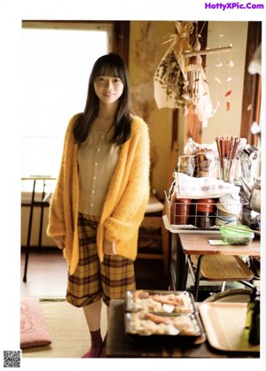 A young woman in a blue sweater is looking at the camera.