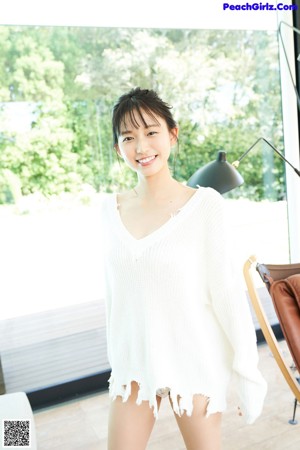A woman in a white sweater is looking out a window.