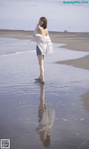 A woman in a black bikini standing by a window.