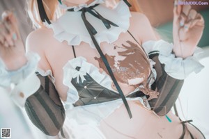 A woman in a maid outfit laying on a bed.