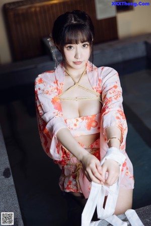 A woman in a pink kimono sitting on the steps of a building.