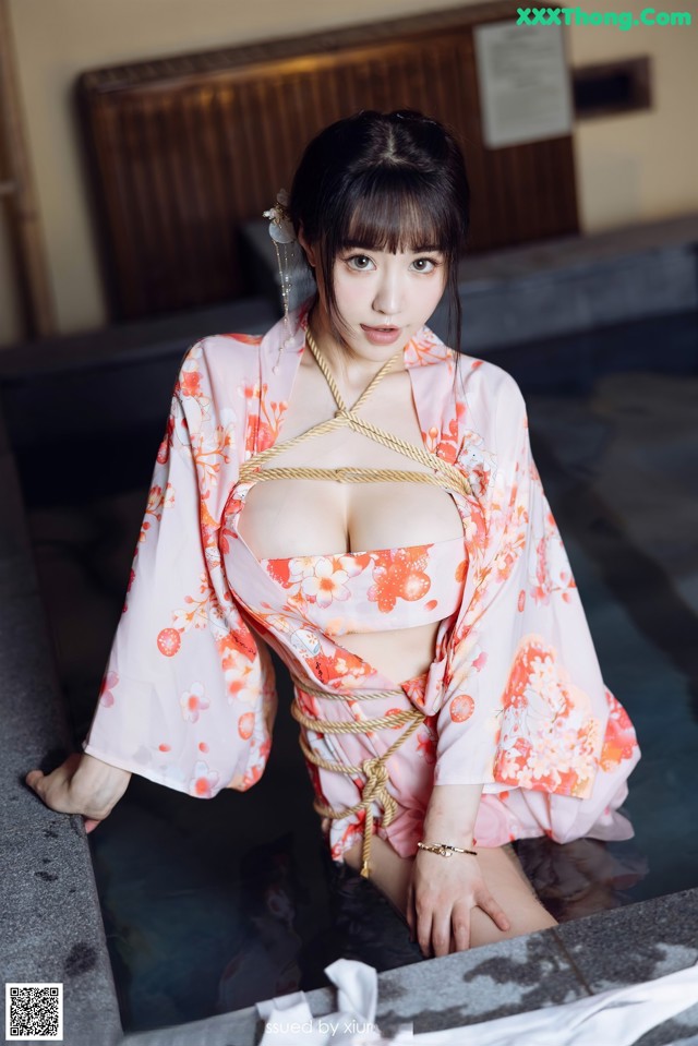 A woman in a pink kimono is tied up in a bathtub.