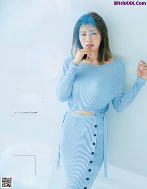 A woman in a blue sweater and skirt posing for a magazine.