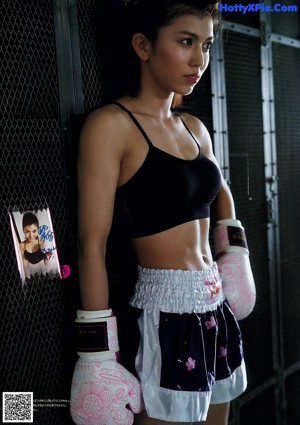 A woman in a pink top and black shorts doing a kick.