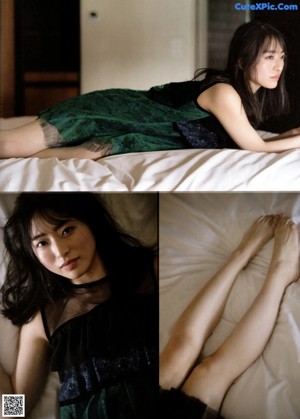 A woman laying on top of a bed in a black dress.