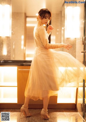 A woman sitting on top of a bathtub next to a mirror.