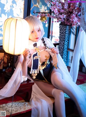 A woman sitting on top of a bed next to a lamp.