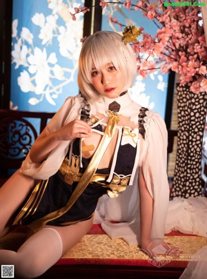 A woman in a maid outfit sitting on a bed.