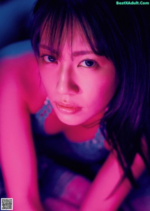 A woman in a blue bikini sitting on a stool.