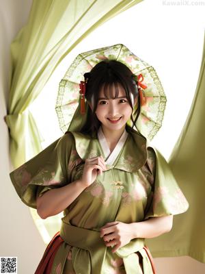 A woman in a blue and pink kimono sitting on a bed.