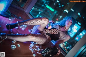 A woman in fishnet stockings sitting on a wooden floor.