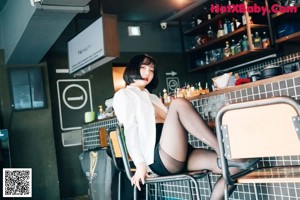 A woman in black stockings and a white shirt posing in a restaurant.