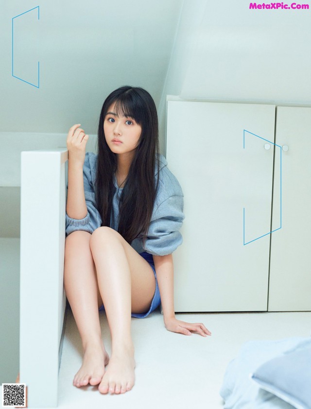 A woman sitting on the floor next to a white cabinet.