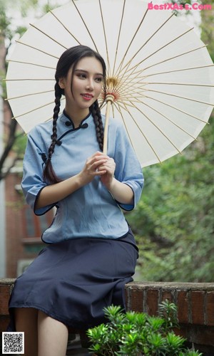 A woman in a white top and black shorts sitting on a window sill.