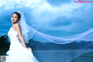 A woman in a wedding dress standing on a dock.