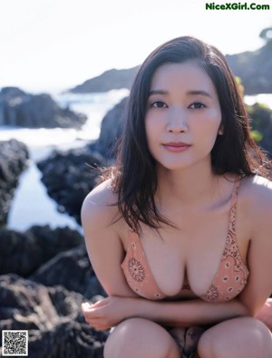 A woman in a black bikini standing on a beach.